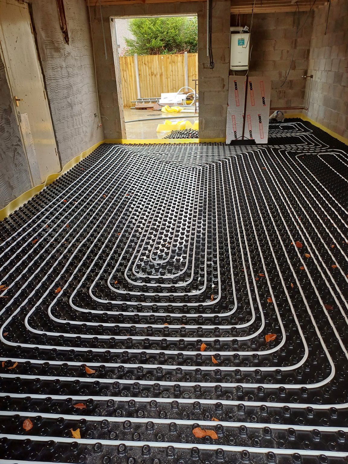 Underfloor heating pipe loops laid across insulation boards in a large extension