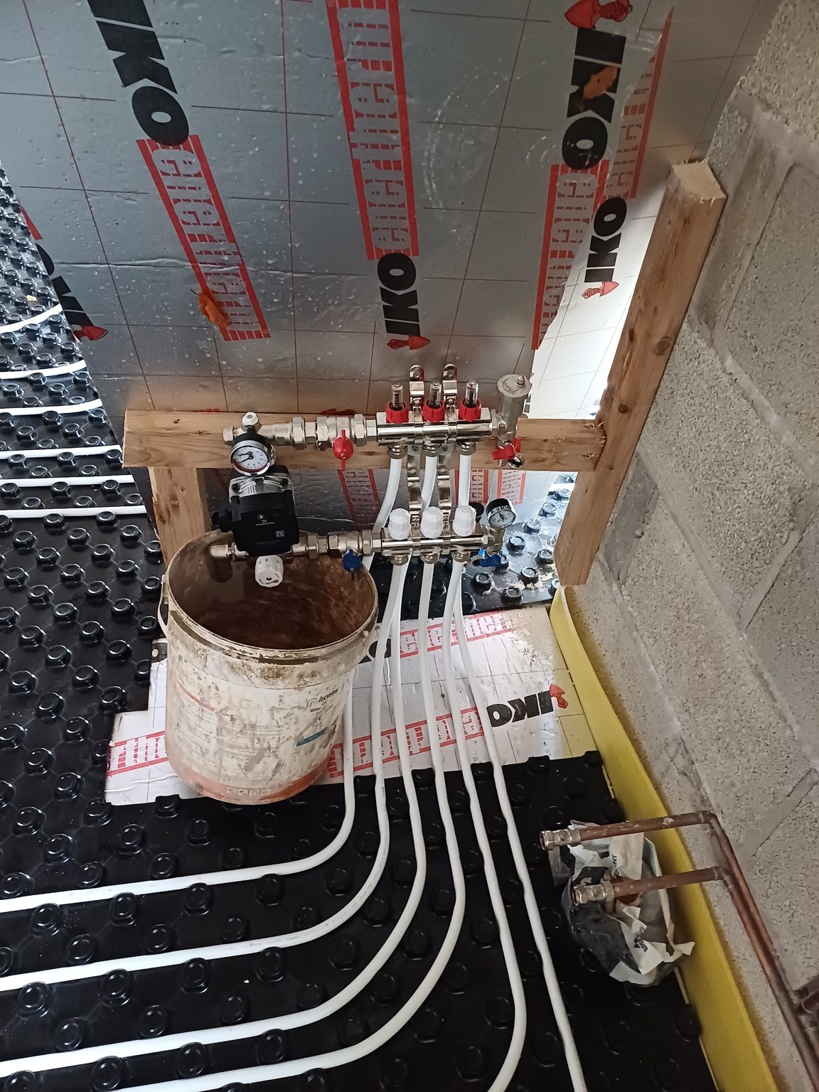 Underfloor heating manifold with pipe runs leading across the insulation