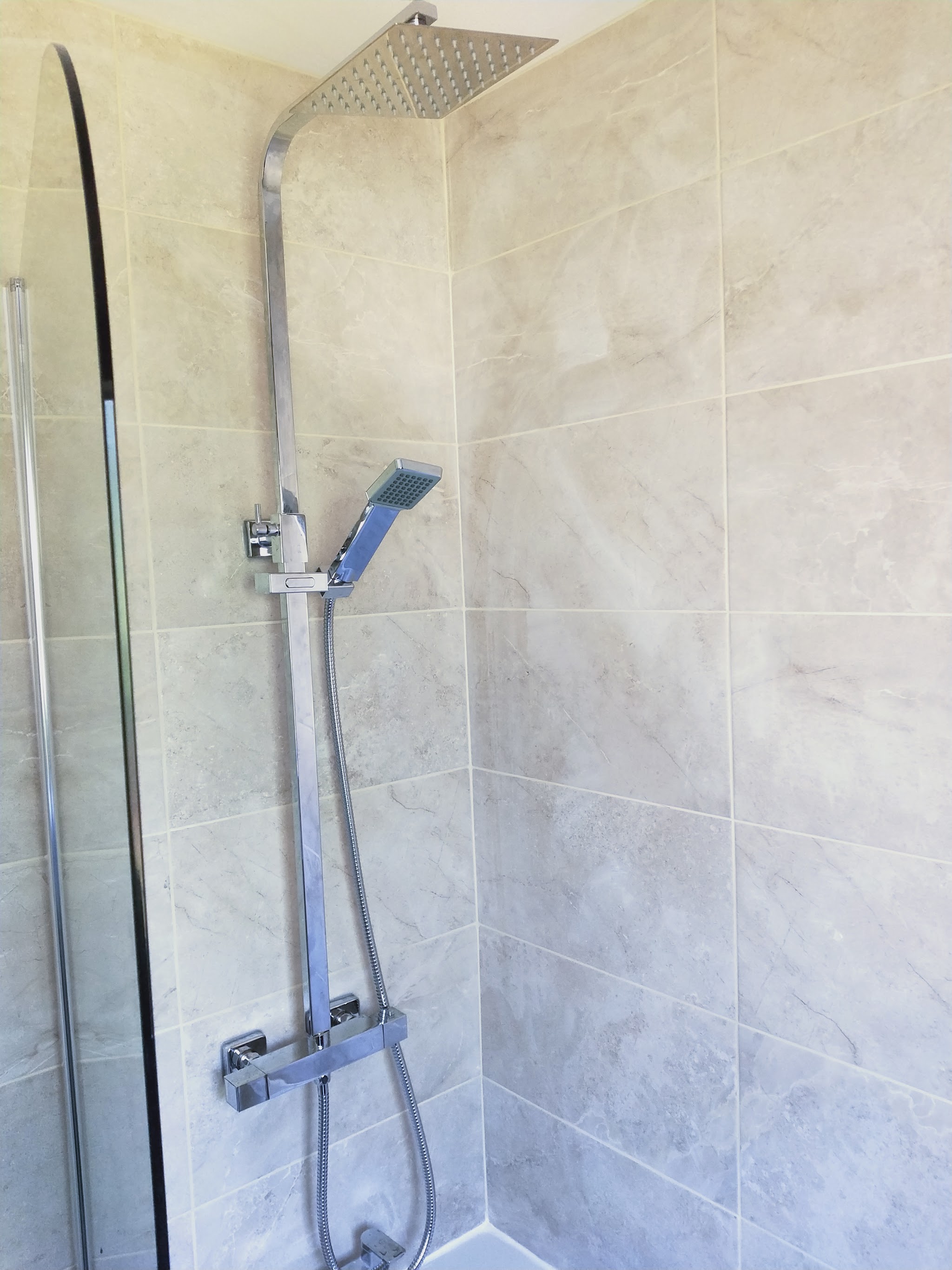 Finished shower with square rainfall head and handset against grey marble-effect tiles
