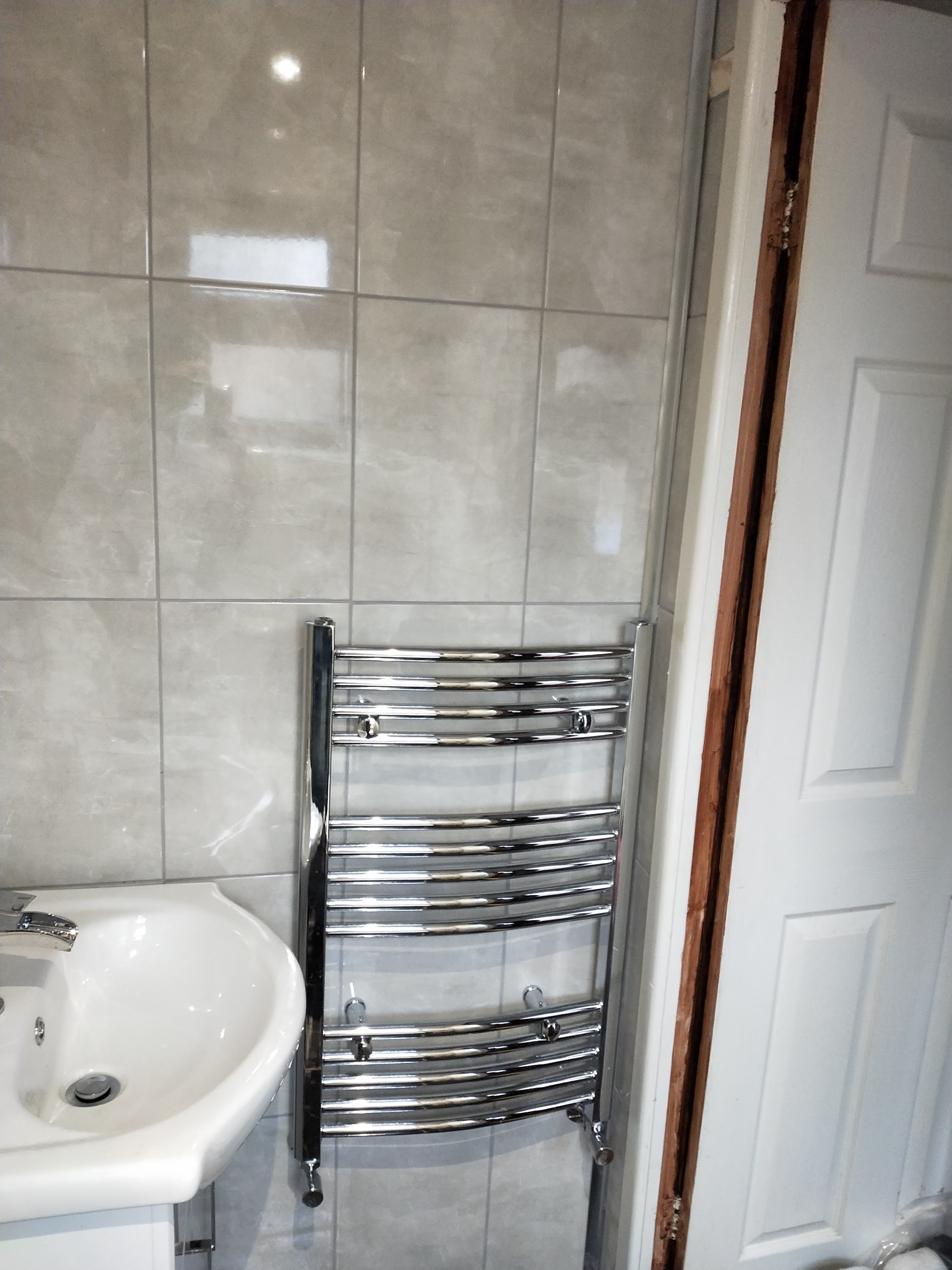 Chrome curved towel rail beside a basin in a newly tiled bathroom
