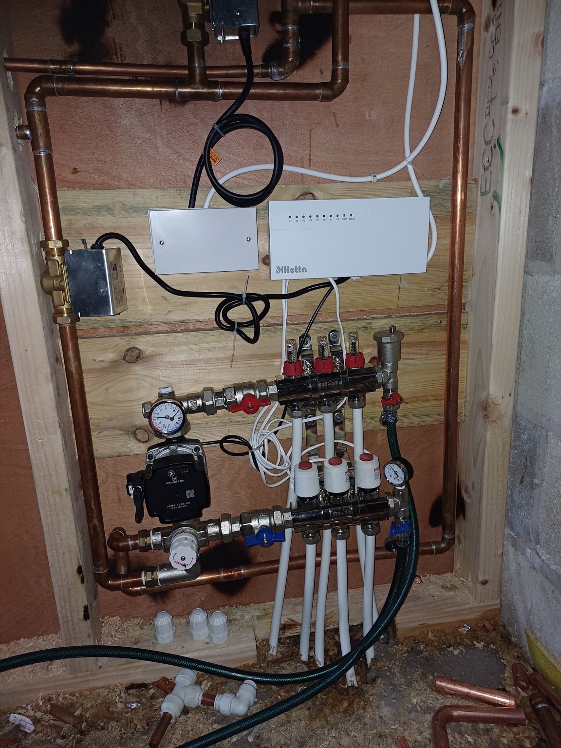 Underfloor heating manifold with pump, gauges and wiring centre on copper pipework